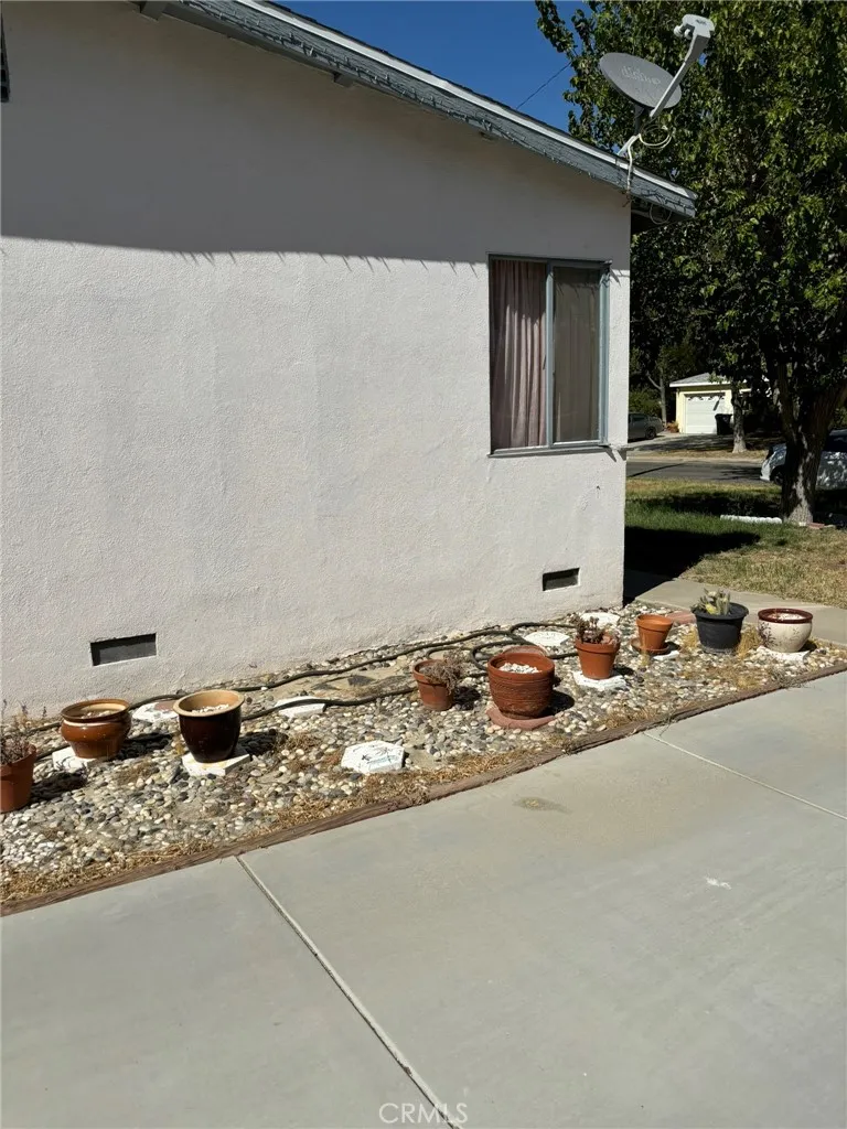 Side view facing front yard with rock border landscaping, and potted plants.