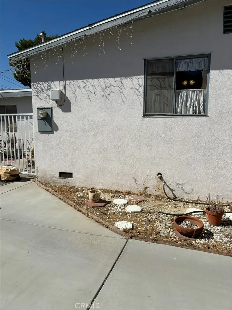 Side exterior view facing backyard area, showing concrete path, utility meter, and low-maintenance landscaping with planter space.
