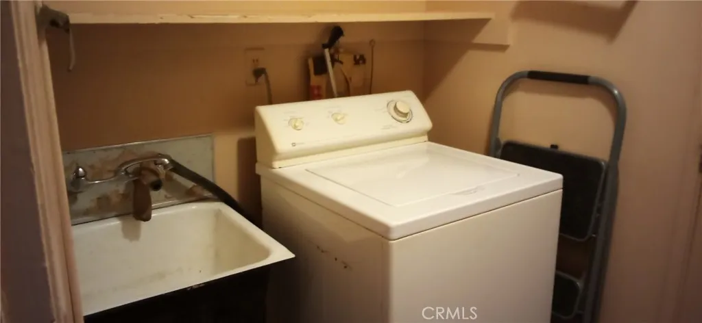 Washing machine next to wash basin in laundry area.