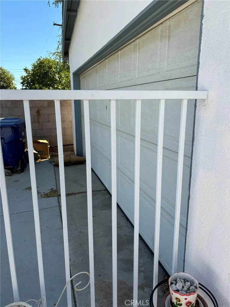 Side-facing view of detached garage and driveway as seen through wrought iron fence.
