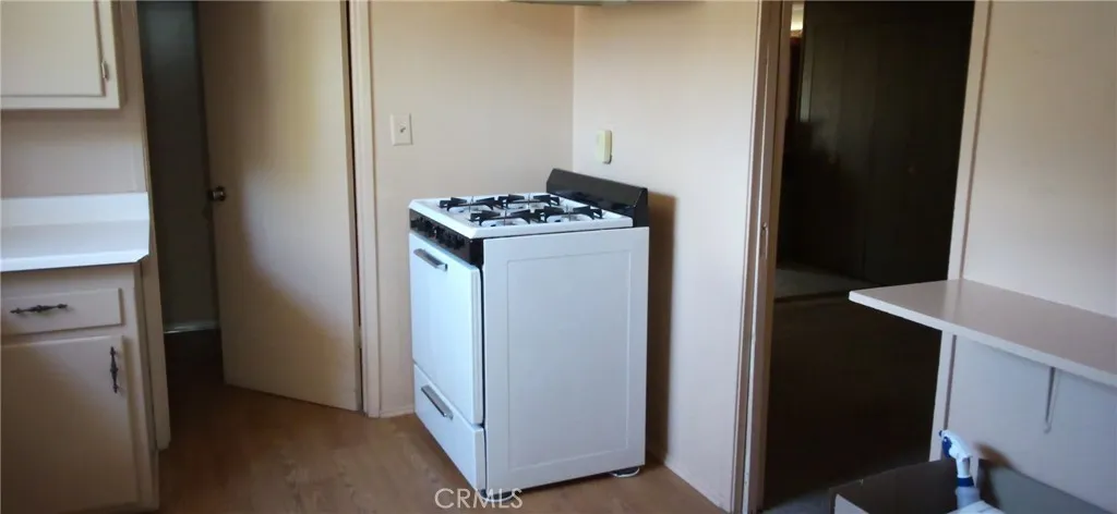 Freestanding gas range and laminate flooring next to entrance to laundry area.