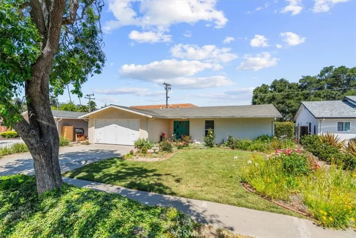 Inviting front yard has rose bushes around entry door and many other flowers to enjoy.
