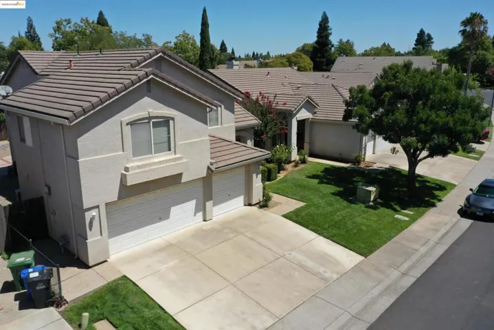 Ranch-style house with a tiled roof, stucco siding, driveway, a front yard, and an attached garage