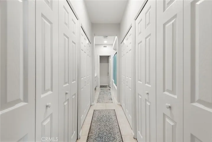 A hallway from the primary bedroom leads to the en-suite bath, flanked by two spacious closets on either side.