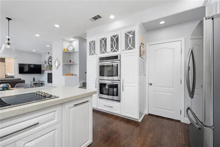 Stainless steel appliances include a 4-burner electric cooktop, double ovens, built-in microwave, and dishwasher.