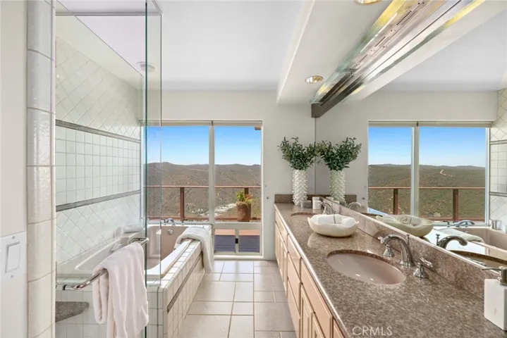 A luxurious en-suite bath complete with dual sinks, soaking tub, separate shower, and private water closet.