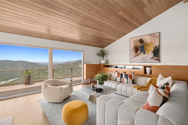 A gated courtyard entry introduces a sense of seclusion and tranquility, opening to an airy, light-filled interior with floor-to-ceiling glass doors that frame breathtaking vistas and create a seamless connection to the oversized entertainer’s deck.