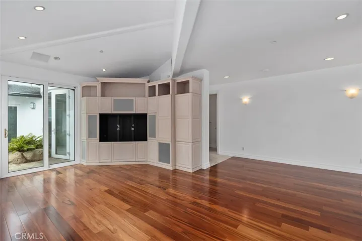 Family room has built-in cabinets and glass doors and windows open to the private pool area and water features.
