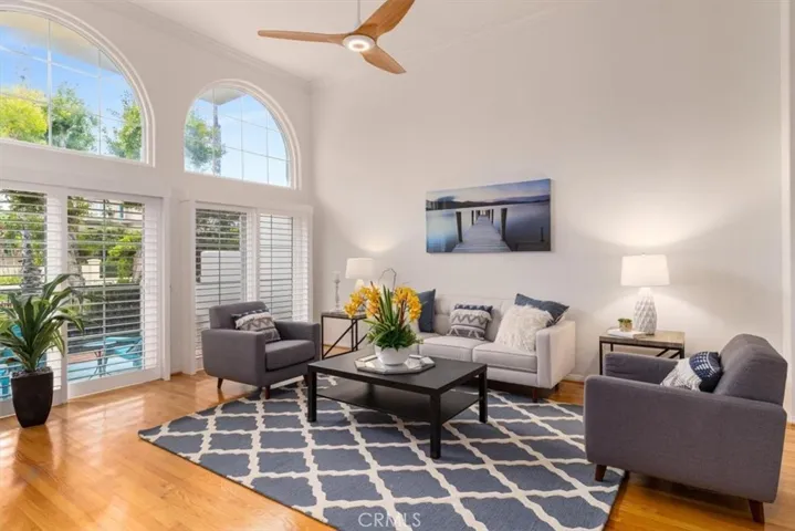 Bright and beachy living room with beautiful hardwood floors and two sliding glass doors that open to a spacious front patio—perfect for seamless indoor-outdoor coastal living.