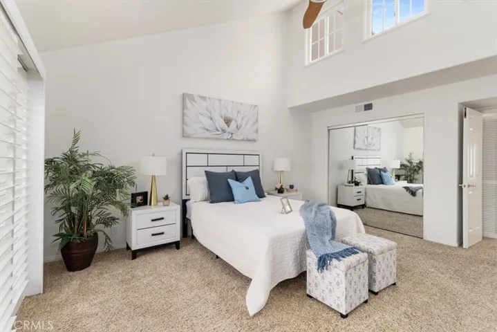 Expansive primary bedroom featuring soaring cathedral ceilings, elegant crown molding, and a warm, airy ambiance filled with natural light—your peaceful coastal retreat.