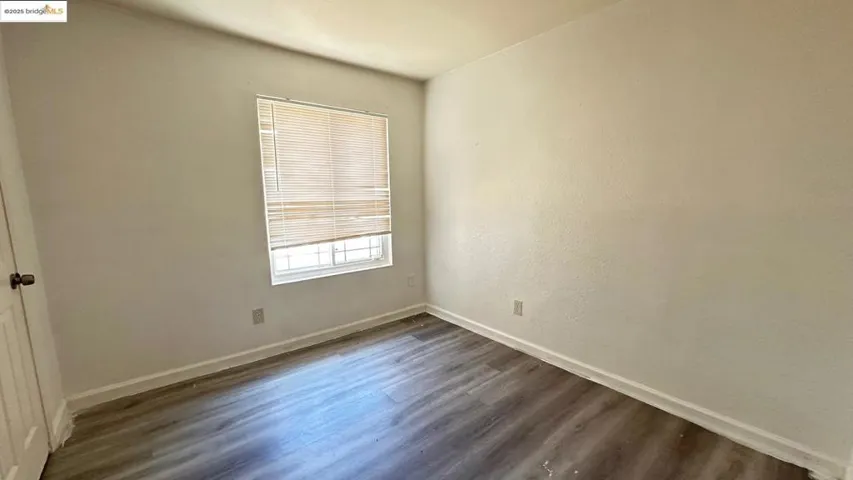 Empty room featuring dark wood-style floors and baseboards