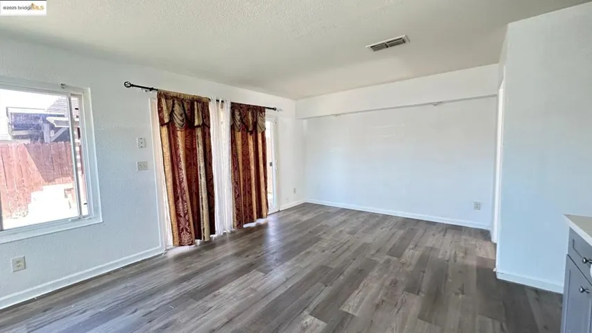 Empty room featuring dark wood finished floors, plenty of natural light, and a textured ceiling