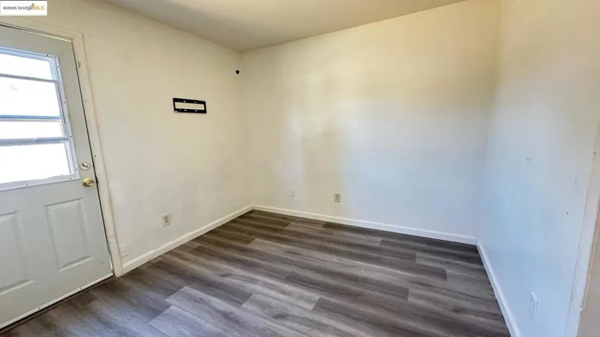 Unfurnished room featuring plenty of natural light and dark wood-style floors