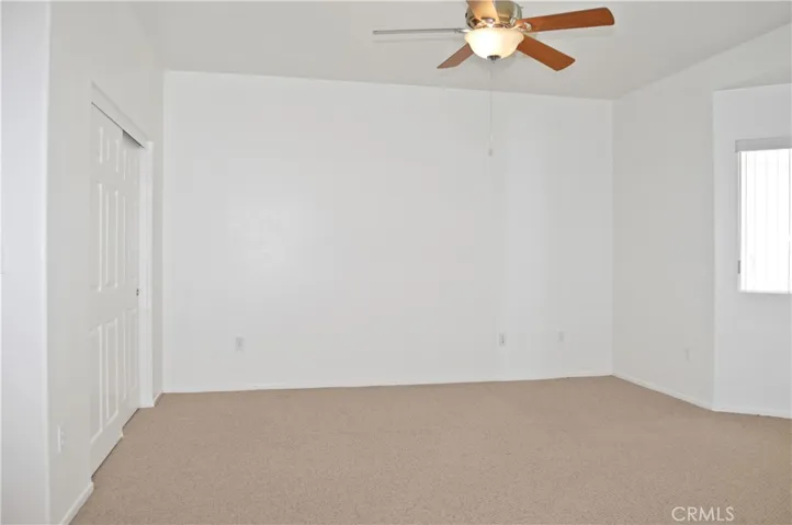Primary Bedroom Suite with Arched Entry to Ensuite Bath, Two Closets (One a Walk-in), Ceiling Fan, and Back Patio Views