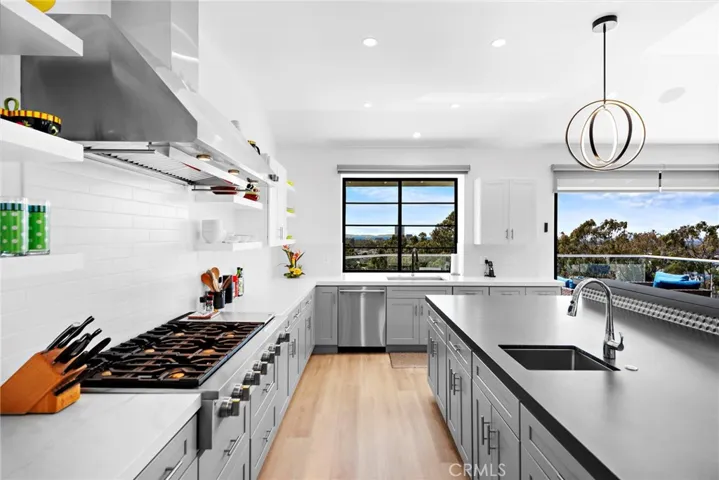 Chef's kitchen with 6 gas burner cook-top, an island with a prep sink and beautiful stone counter top.