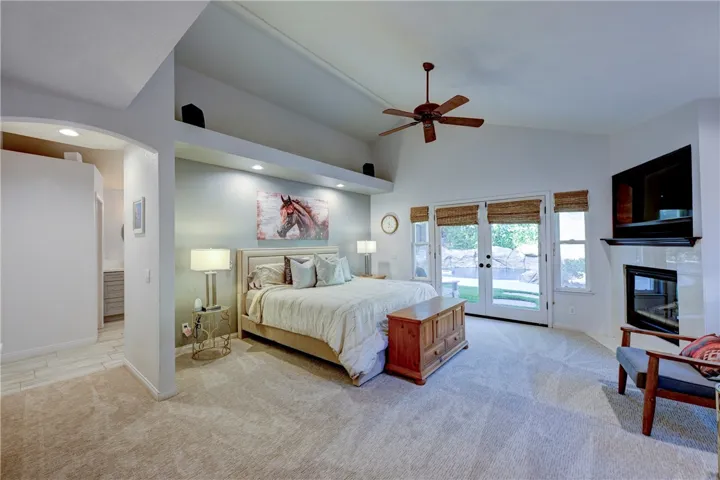Spacious primary suite with fireplace, ceiling fan and French doors to the backyard.
