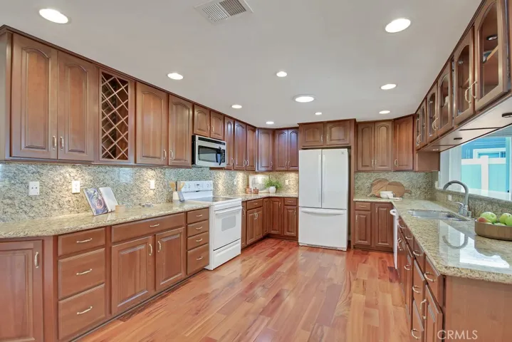 Spacious kitchen with rich wood cabinetry, granite countertops, under-cabinet lighting, and a large breakfast counter—designed for both style and functionality.