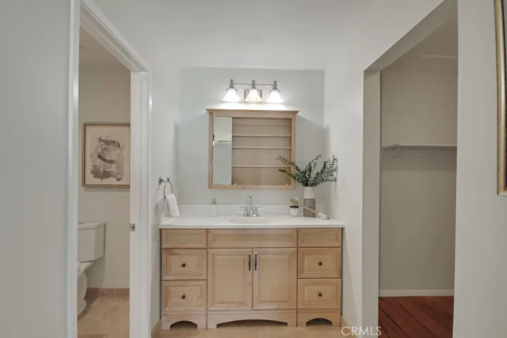 The primary bathroom includes a spacious vanity, walk-in closet with wood flooring, and private water closet—offering a functional and private retreat.