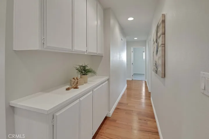 Hallway with recessed lighting, built-in linen cabinets, and warm wood flooring—leading to the private bedroom wing of the home.