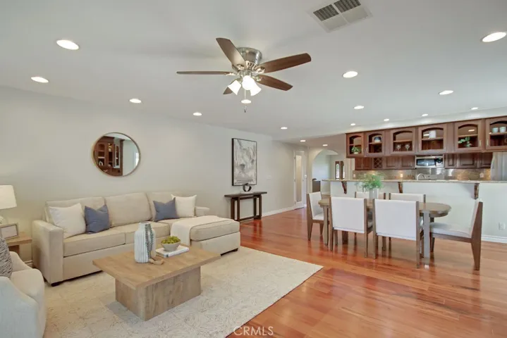 Light and open family room seamlessly connected to dining and kitchen spaces—featuring recessed lighting, wood floors, ceiling fan, and a warm, welcoming layout for everyday living and entertaining.