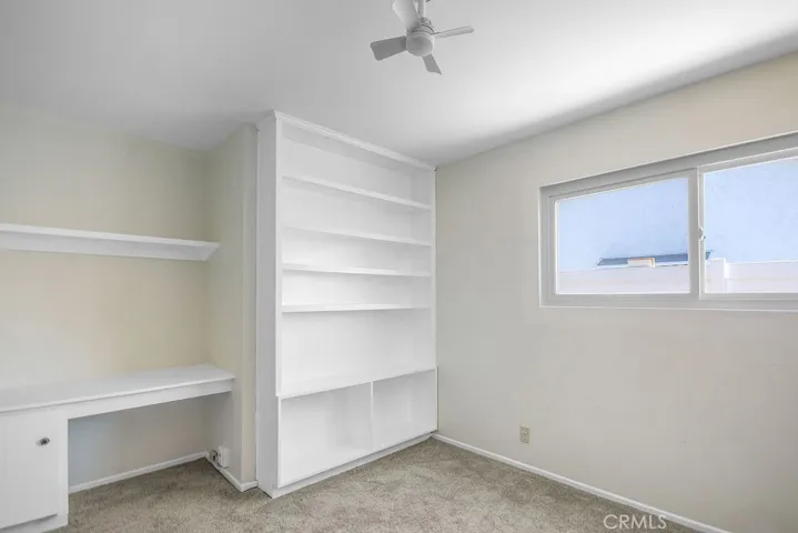 Versatile fourth bedroom with bookshelf, desk, and new carpet—ideal for a home office, study, or guest room.