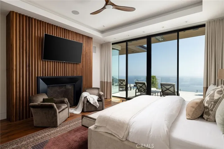 The primary bedroom is highlighted by a custom walnut-clad fireplace, custom closets, blackout shades, ceiling fan and priceless views.