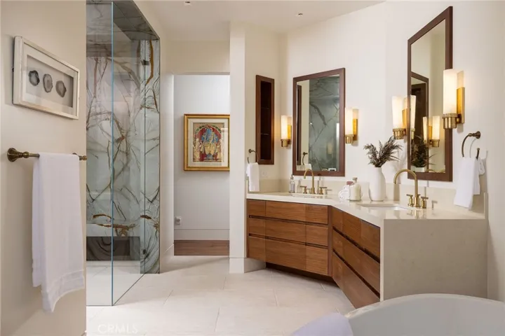 The spa-inspired primary bath features quartzite surfaces, steam shower, freestanding jacuzzi tub, and custom walnut cabinetry.