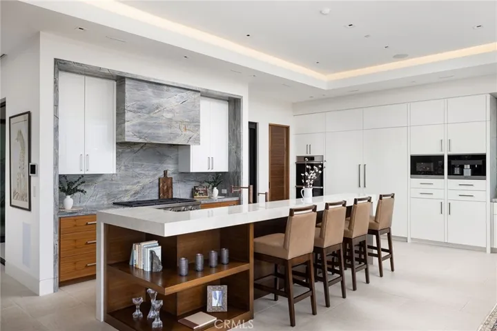 The open-concept, gourmet kitchen impresses with premium Dacor appliances, Miele built-in coffee station, walk-in pantry, and oversized porcelain and quartzite island.