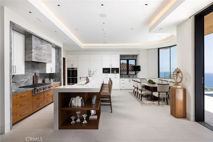 The open-concept, gourmet kitchen impresses with premium Dacor appliances, Miele built-in coffee station, walk-in pantry, and oversized porcelain and quartzite island, ideal for effortless indoor-outdoor entertaining.