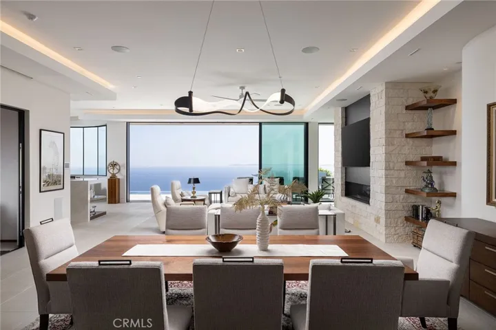 The home's centerpiece is an expansive great room featuring 11.6’ ceilings, sliding glass doors, porcelain floors and custom 75” fireplace, all framing captivating sit-down ocean and pool vistas.
