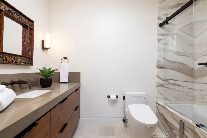 Full secondary bath with stone counters and all-slab stone shower and Toto Washlet toilet.