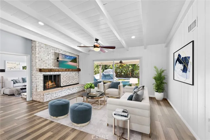 Spacious family room with views of the backyard pool, brick fireplace, and seamless flow to the kitchen and dining area. Opposite the brick fireplace is a second stone fireplace, offering flexibility for use as a living room, secondary family room. Room has been virtually staged.
