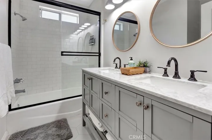 Downstairs Home: Hall bath remodeled with dual sink vanity, quartz and glass door for shower over tub