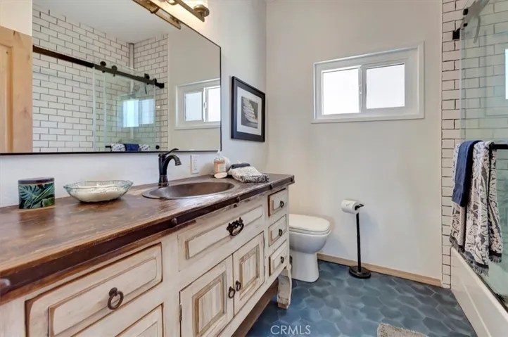 Hall bath with custom wood vanity and barn-door siding glass to tub over shower