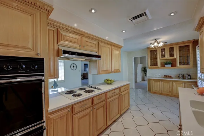Double oven, electric stove top, recessed lighting in this very clean kitchen.