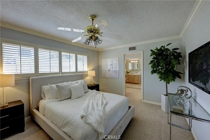 Primary Suite with lighted ceiling fan and plantation shutters.