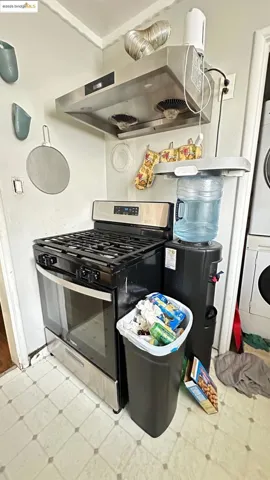 Kitchen featuring gas stove, range hood, and estacked washer and dryer