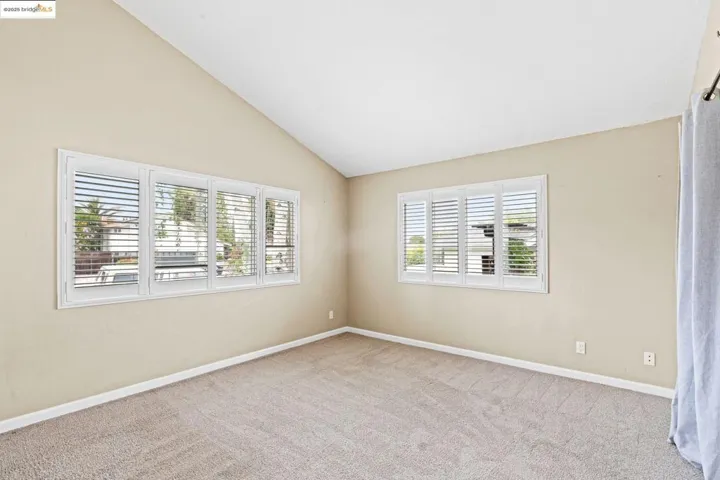 Unfurnished room with carpet and high vaulted ceiling