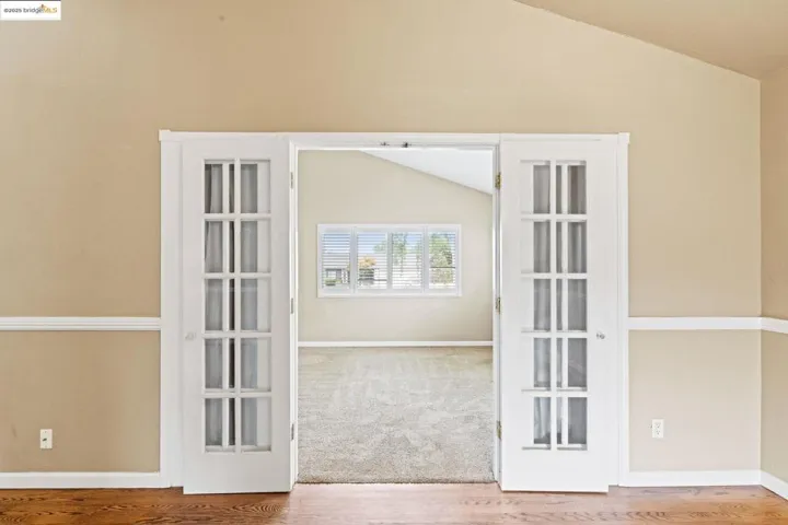 Carpeted empty room with vaulted ceiling and wood finished floors
