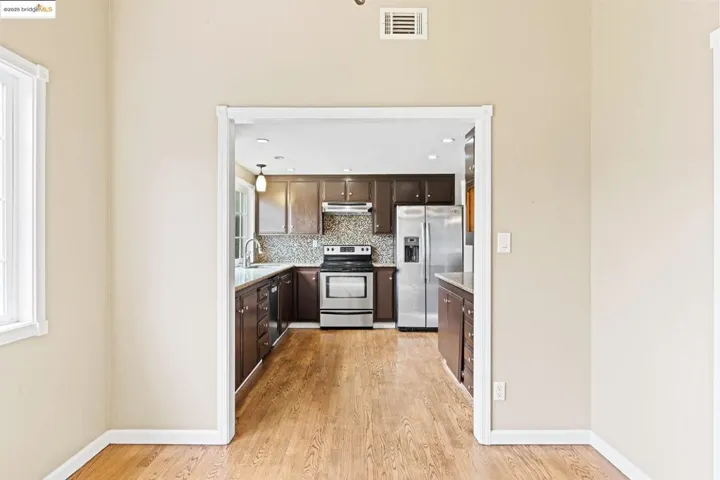 Kitchen featuring appliances with stainless steel finishes, tasteful backsplash, dark brown cabinets, light wood-style floors, and recessed lighting