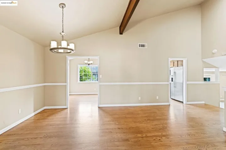 Spare room with a chandelier, wood finished floors, beamed ceiling, and high vaulted ceiling