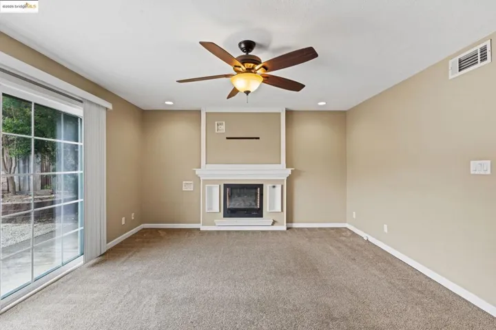 Unfurnished living room with carpet, a fireplace, ceiling fan, and recessed lighting