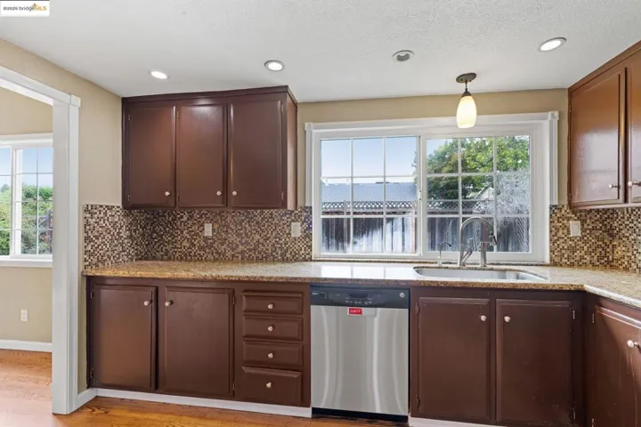 Kitchen featuring stainless steel dishwasher, tasteful backsplash, recessed lighting, a textured ceiling, and hanging light fixtures