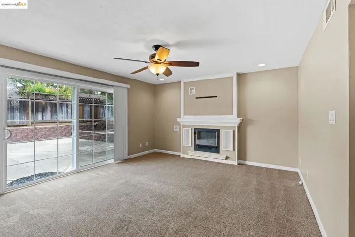 Unfurnished living room featuring a glass covered fireplace, a ceiling fan, carpet floors, and recessed lighting