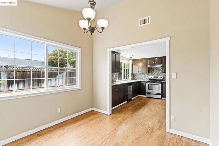 Kitchen featuring stainless steel appliances, light wood-type flooring, decorative backsplash, dark brown cabinets, and light countertops