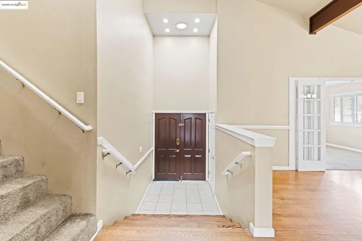 Foyer entrance featuring beamed ceiling, wood finished floors, stairs, and high vaulted ceiling