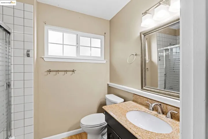 Full bathroom with a shower stall, vanity, and wood finished floors