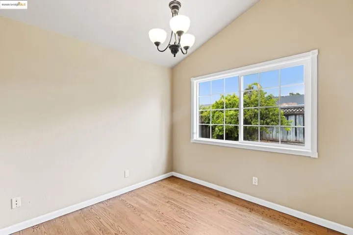 Unfurnished room featuring vaulted ceiling, a chandelier, and wood finished floors