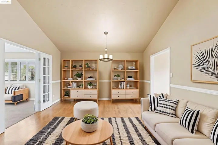 Living area with light wood finished floors, lofted ceiling, and a chandelier