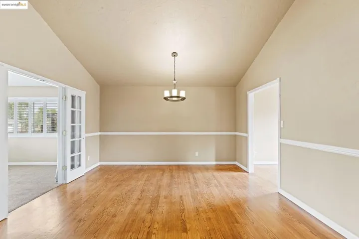 Unfurnished dining area featuring lofted ceiling, light wood-style flooring, and a chandelier